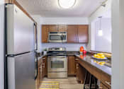Thumbnail 15 of 25 - A kitchen with a stainless steel refrigerator and wooden cabinets.