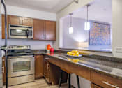 Thumbnail 14 of 25 - A kitchen with a stove top oven, microwave, and a counter with a bowl of lemons on it.