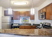Thumbnail 20 of 25 - A kitchen with brown cabinets and granite countertops.