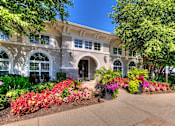 Thumbnail 50 of 53 - A white building with a large arched doorway and windows flanked by flower beds.