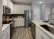 Thumbnail 6 of 53 - A modern kitchen with white cabinets and stainless steel appliances.
