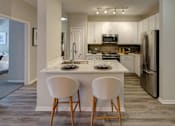 Thumbnail 5 of 53 - A kitchen with a white countertop and two white chairs.