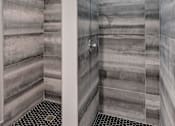 Thumbnail 32 of 53 - A bathroom with a tiled shower and a black and white floor.