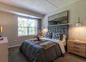 Thumbnail 9 of 53 - A bedroom with a large bed and a wooden nightstand.