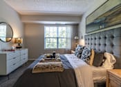 Thumbnail 8 of 53 - A bedroom with a large bed, a dresser, and a painting on the wall.