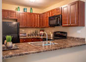 Thumbnail 25 of 31 - A kitchen with brown cabinets and a black refrigerator.