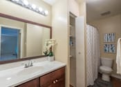 Thumbnail 29 of 31 - A bathroom with a sink, mirror, toilet, and shower.