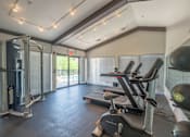 Thumbnail 18 of 31 - A gym with a treadmill, a weight machine, and a rowing machine.