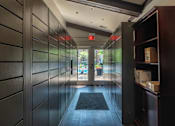 Thumbnail 20 of 31 - A hallway with a black door mat and a red exit sign.