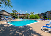 Thumbnail 22 of 31 - A swimming pool surrounded by lounge chairs and trees.
