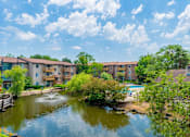 Thumbnail 5 of 31 - A pond in front of apartment buildings on a sunny day.