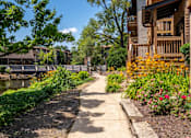 Thumbnail 6 of 31 - A walkway runs through a lush green garden.
