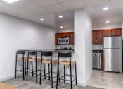 Thumbnail 58 of 62 - A kitchen with a refrigerator, microwave, oven, and bar stools.
