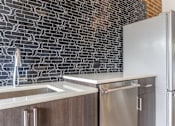 Thumbnail 57 of 62 - A kitchen with a stainless steel refrigerator and a sink.