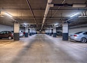 Thumbnail 31 of 62 - A parking garage with cars parked on both sides of the aisle.