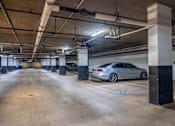 Thumbnail 32 of 62 - A car is parked in a large, empty parking garage.