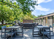 Thumbnail 21 of 62 - A patio with a table and chairs is surrounded by trees.