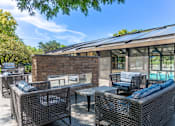 Thumbnail 22 of 62 - A patio with a table and chairs and a pool in the background.