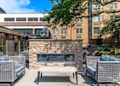 Thumbnail 20 of 62 - A patio with a stone fireplace and wicker chairs.