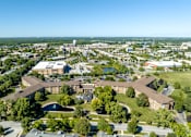 Thumbnail 61 of 62 - A large building complex with a green lawn in front.