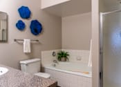 Thumbnail 15 of 62 - A bathroom with a toilet, sink, and a bathtub with a plant in it.