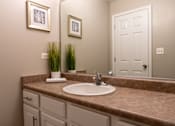 Thumbnail 26 of 43 - A bathroom with a brown granite countertop and a white sink.