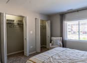 Thumbnail 19 of 43 - A bedroom with a bed, chair, and three closets.