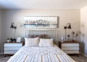 Thumbnail 18 of 43 - A bedroom with a bed, two nightstands, and a painting on the wall.