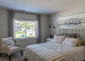 Thumbnail 17 of 43 - A bedroom with a large bed and a chair by the window.