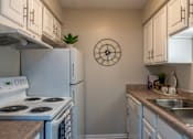 Thumbnail 9 of 43 - A white stove and oven in a kitchen with a clock on the wall.