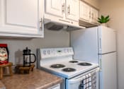 Thumbnail 11 of 43 - A white stove with a kettle on it in a kitchen.