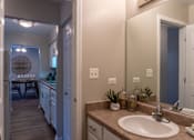 Thumbnail 27 of 43 - A bathroom with a sink, mirror, and a view of a dining area.