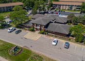 Thumbnail 42 of 43 - A parking lot with cars and a building in the background.