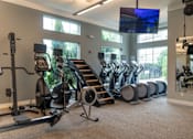Thumbnail 54 of 73 - A gym with a row of treadmills and elliptical machines.
