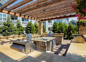 Thumbnail 31 of 73 - A patio with a grill and a table under a wooden pergola.