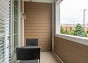 Thumbnail 20 of 73 - A black chair sits on a balcony with a view of trees and a cloudy sky.