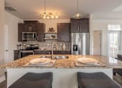 Thumbnail 5 of 73 - A kitchen with granite countertops and dark brown cabinets.