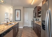 Thumbnail 3 of 73 - A kitchen with a granite countertop and stainless steel appliances.