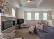 Thumbnail 6 of 73 - A living room with a grey couch and a fireplace.