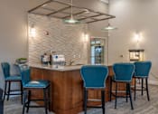 Thumbnail 47 of 73 - A bar area with blue chairs and a white brick wall.