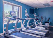 Thumbnail 22 of 25 - A gym with treadmills and a television.