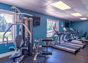 Thumbnail 23 of 25 - A gym with a variety of equipment including treadmills, weights, and exercise machines.