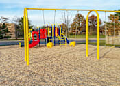 Thumbnail 18 of 25 - A playground with a yellow swing set and a red slide.
