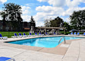 Thumbnail 16 of 25 - A swimming pool surrounded by chairs and trees.