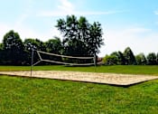 Thumbnail 15 of 25 - A volleyball net is set up on a sandy court.