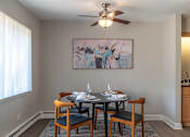 Thumbnail 3 of 25 - A dining room with a table set for two and a painting on the wall.