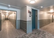 Thumbnail 13 of 25 - A long hallway with doors on both sides and a tiled floor.