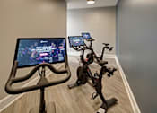 Thumbnail 30 of 53 - A room with a stationary bike and a screen showing a video game.