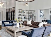 Thumbnail 21 of 53 - A modern living room with a brown leather couch and blue chairs.