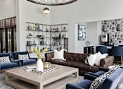 Thumbnail 20 of 53 - A living room with a dark blue sofa, a brown leather couch, and a wooden coffee table.